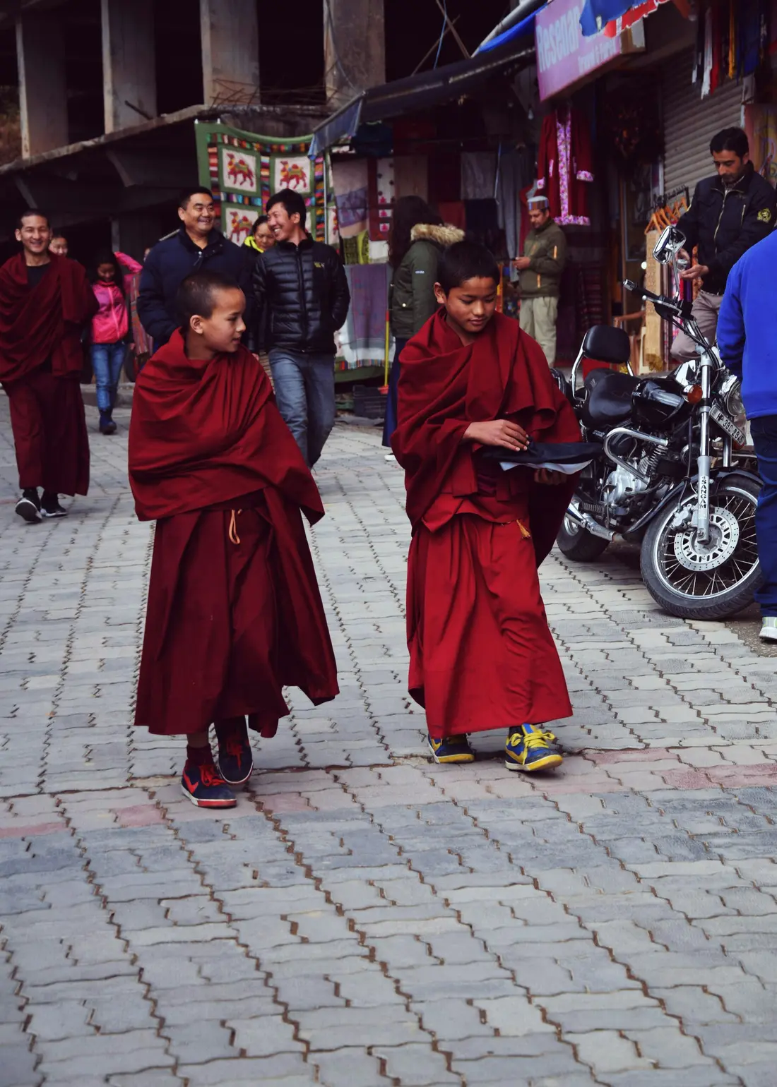 Two monks in maroon robes walking down a street