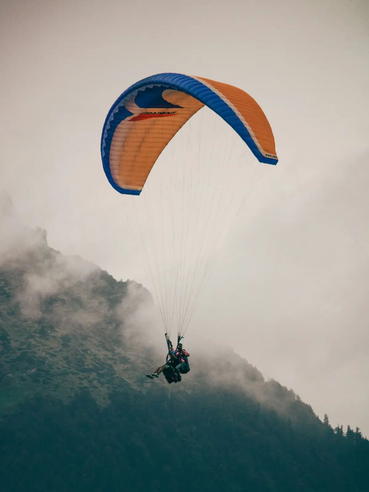 A paraglider launching into fog above the mountains near Manali