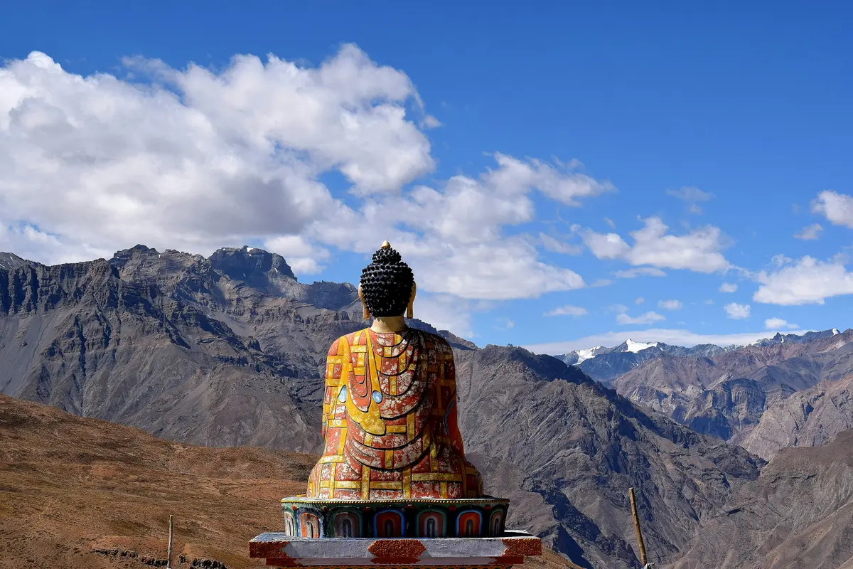 A weathered Buddha statue overlooking the Spiti Valley from behind