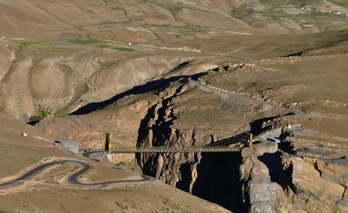 Aerial view of a canyon road switchbacking through the Spiti landscape