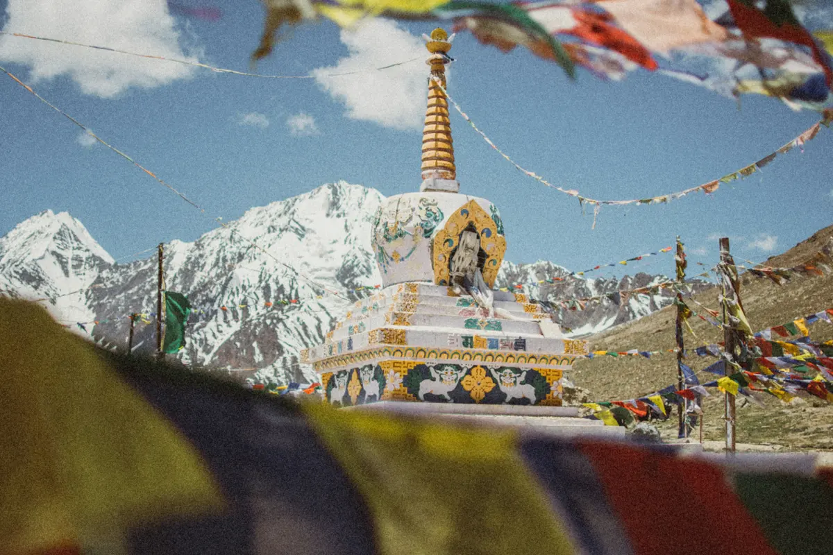 Golden stupa and prayer flags against a snow-capped peak in Spiti